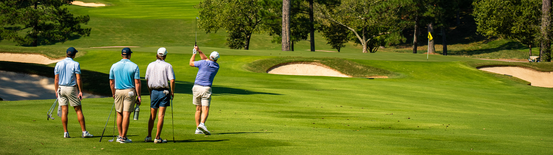 A picture of a beautiful golf course with several golfers enjoying a game.