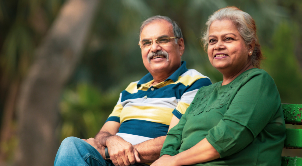 A senior couple sits together on a bench in a park in Decatur, GA.